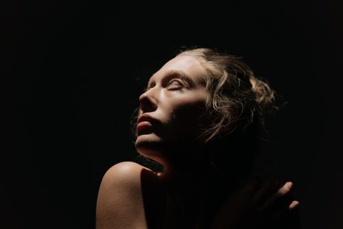 Free Artistic portrait of a woman with dramatic light and shadow contrast. Stock Photo