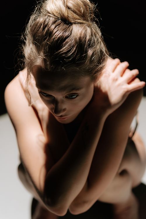Free Artistic portrait of a pensive woman sitting in shadows, capturing raw emotion and beauty. Stock Photo