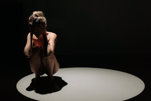 A Scared Woman Crouching while Her Hands are on Her Head