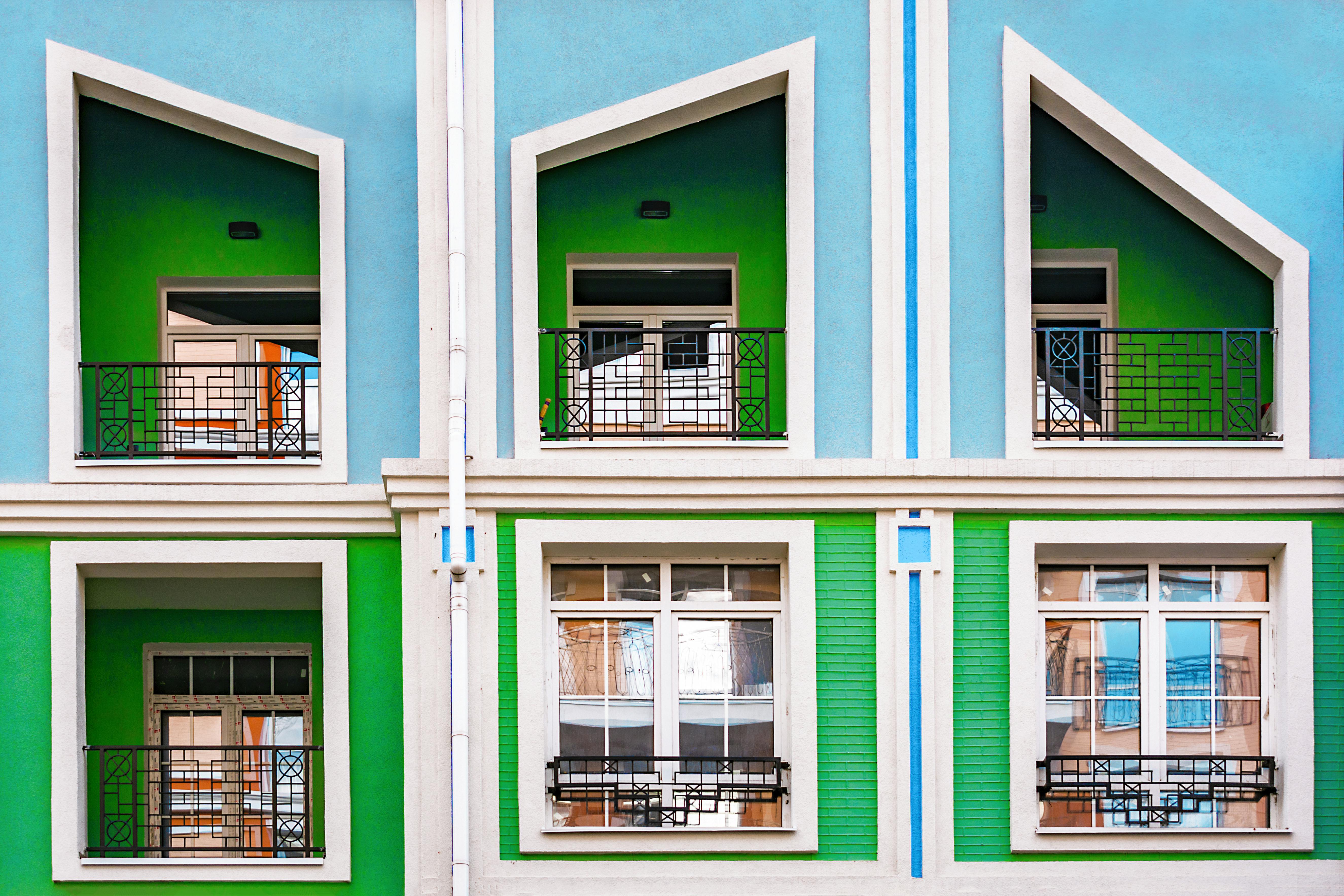 Vibrant blue and green building facade featuring geometric windows and balconies.