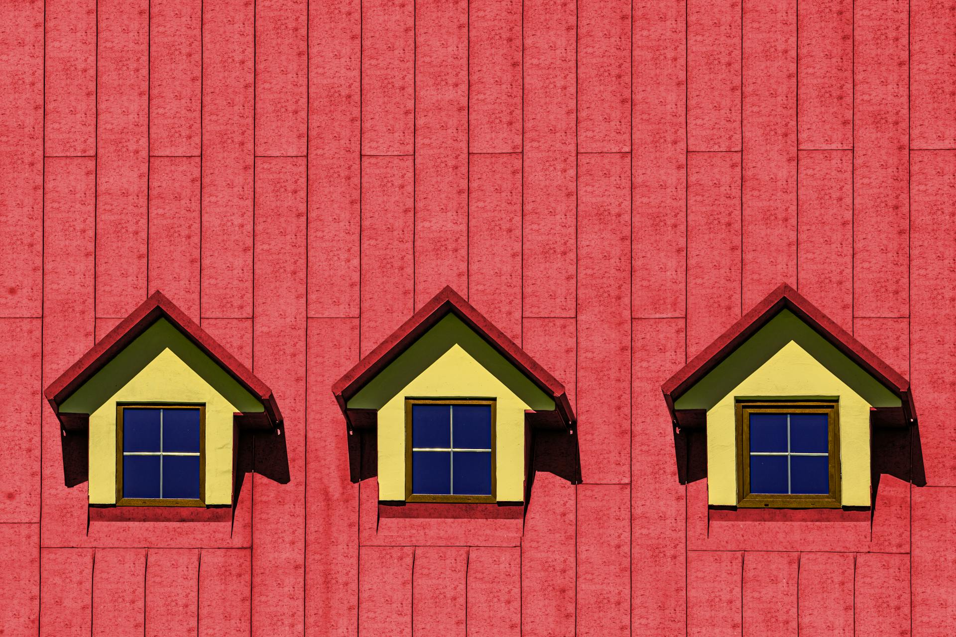 Close-up of a vibrant red roof with three symmetrical dormer windows.