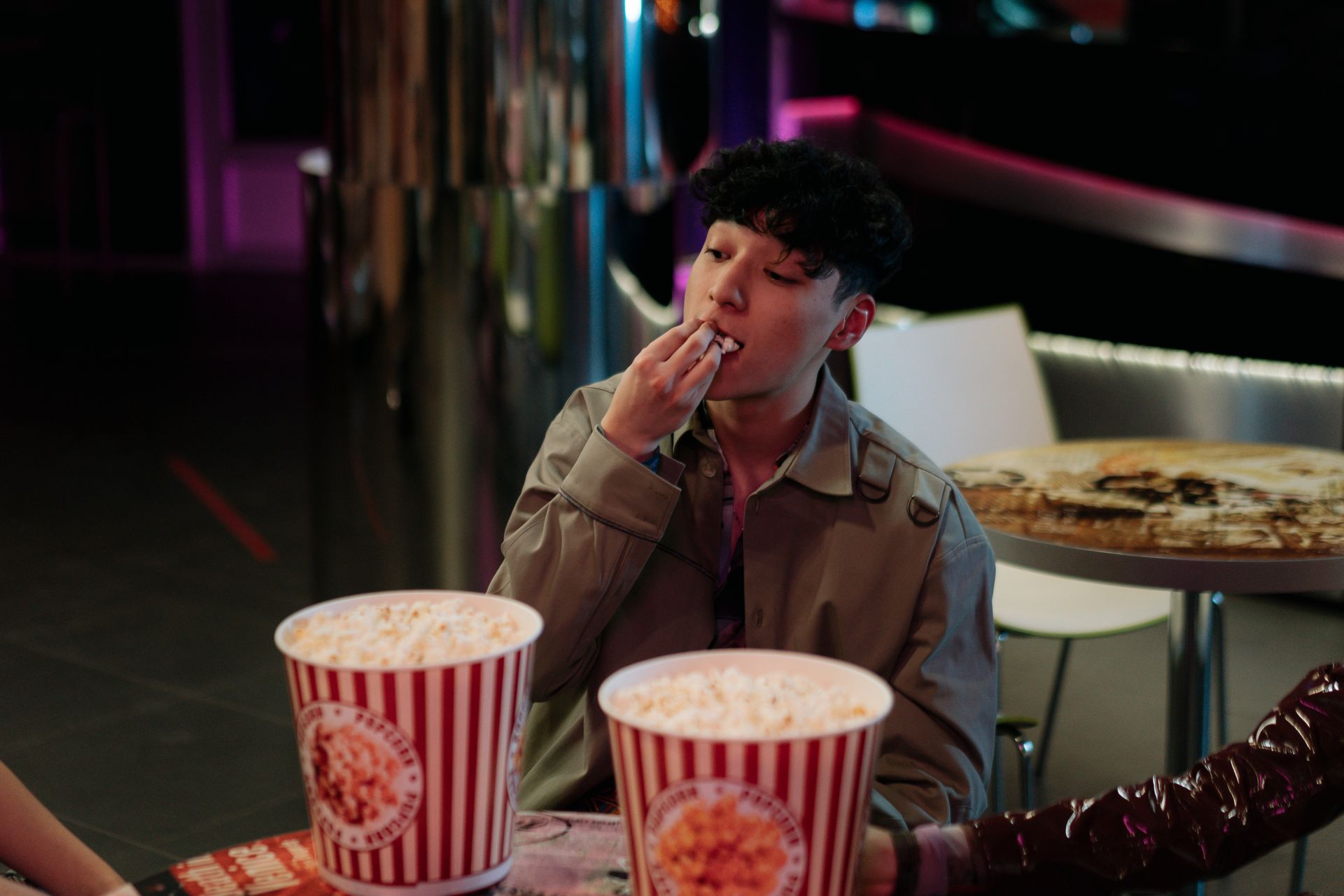 A young man enjoying popcorn at an indoor cinema setting.