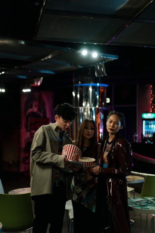 Free Three friends at a cinema holding popcorn and enjoying the night scene. Stock Photo