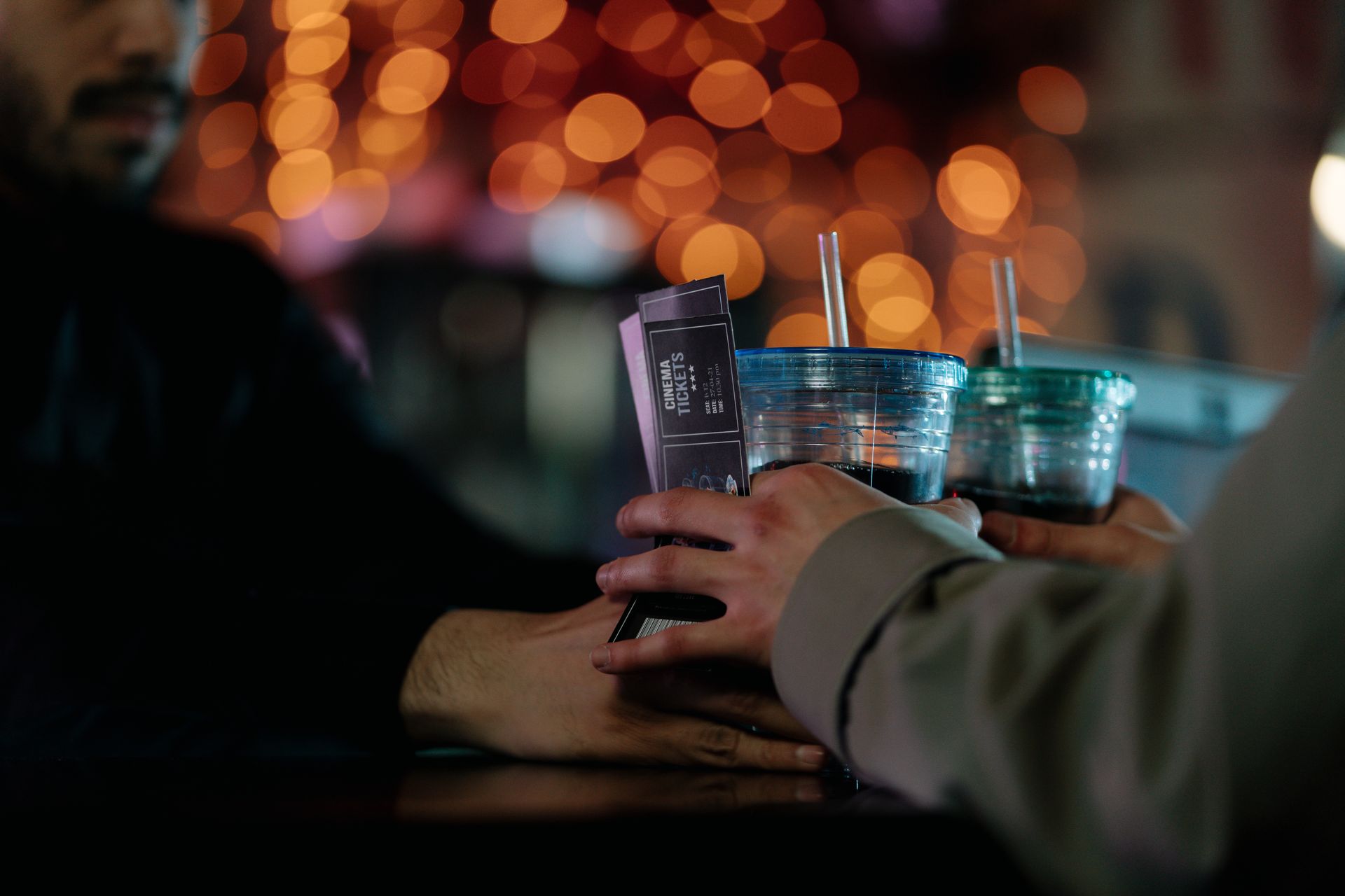 A Bearded Man Handing Out a Couple of Drinks to a Person Holding Cinema Tickets
