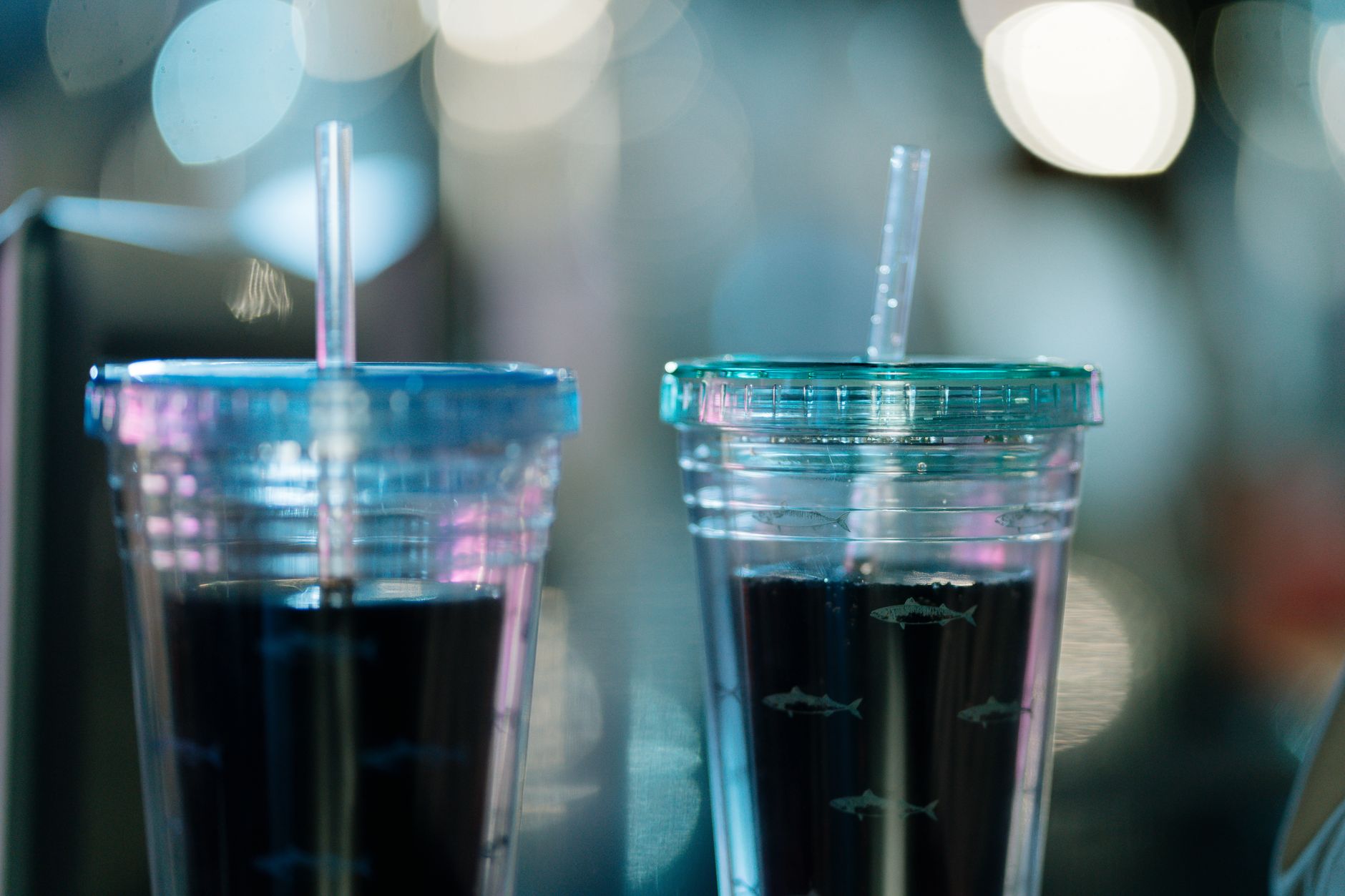 Two disposable cups with straws containing beverages, captured in a still life setting.