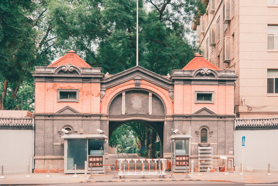 Elegant red brick arched entrance with trees, showcasing Beijing's architectural charm.