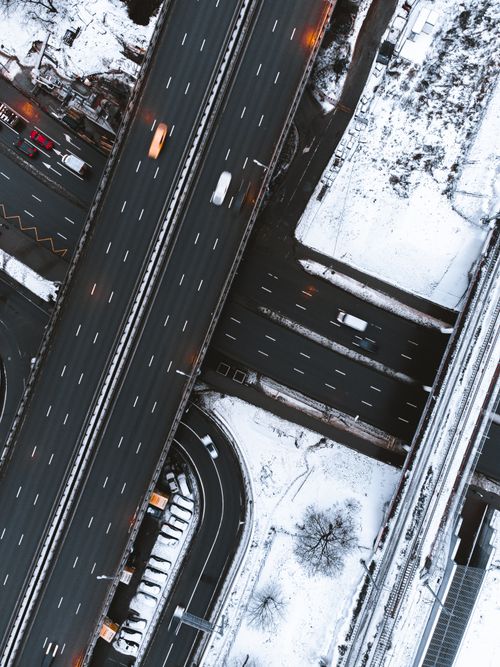 Free Drone shot of a snowy highway intersection with vehicles in winter. Stock Photo