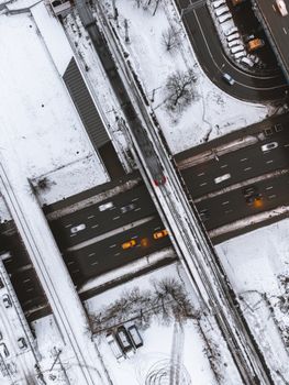 Drone shot capturing snowy roads with moving vehicles and bridges in winter.