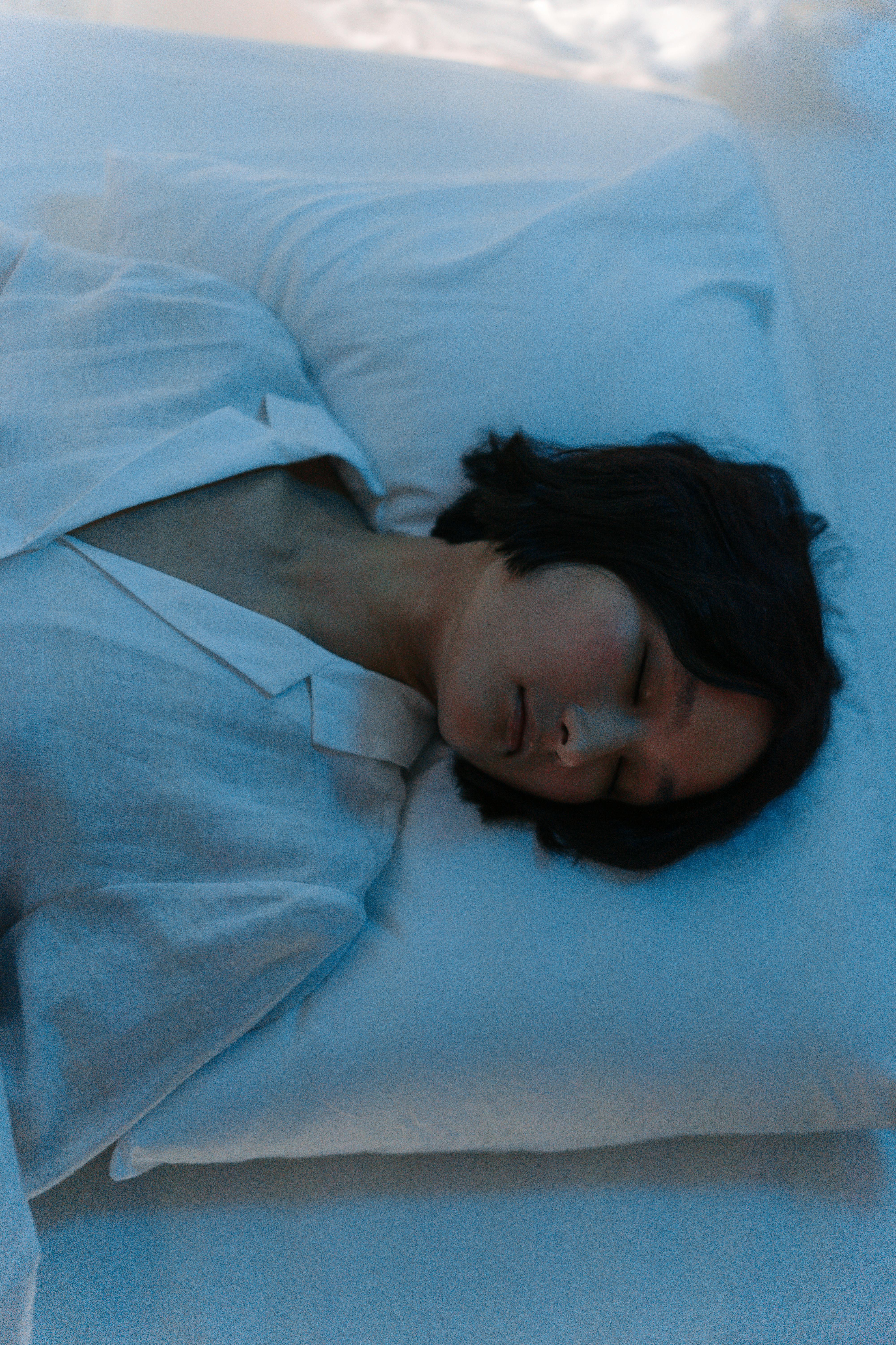 A peaceful woman sleeping on a pillow with eyes closed, captured in soft lighting from above.