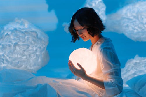 A Woman in White Top Holding a Crystal Ball