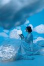 Woman Sitting on White Bed Among Clouds