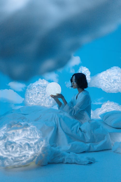 Woman Sitting on White Bed Among Clouds