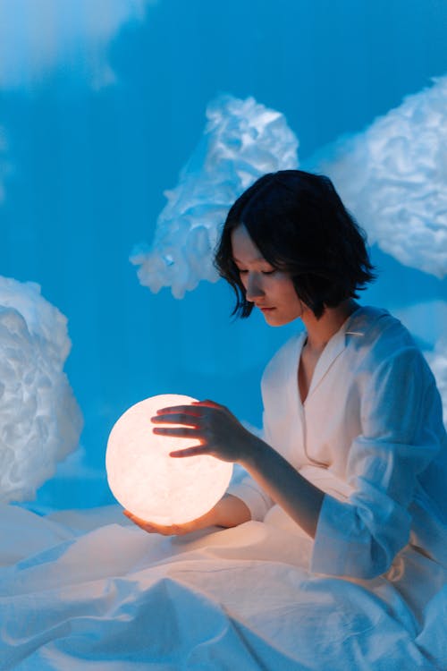 A Woman Looking at the Moon Lamp she is Holding · Free Stock Photo