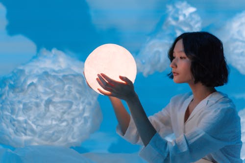 A Woman in White Top Holding a Crystal Ball