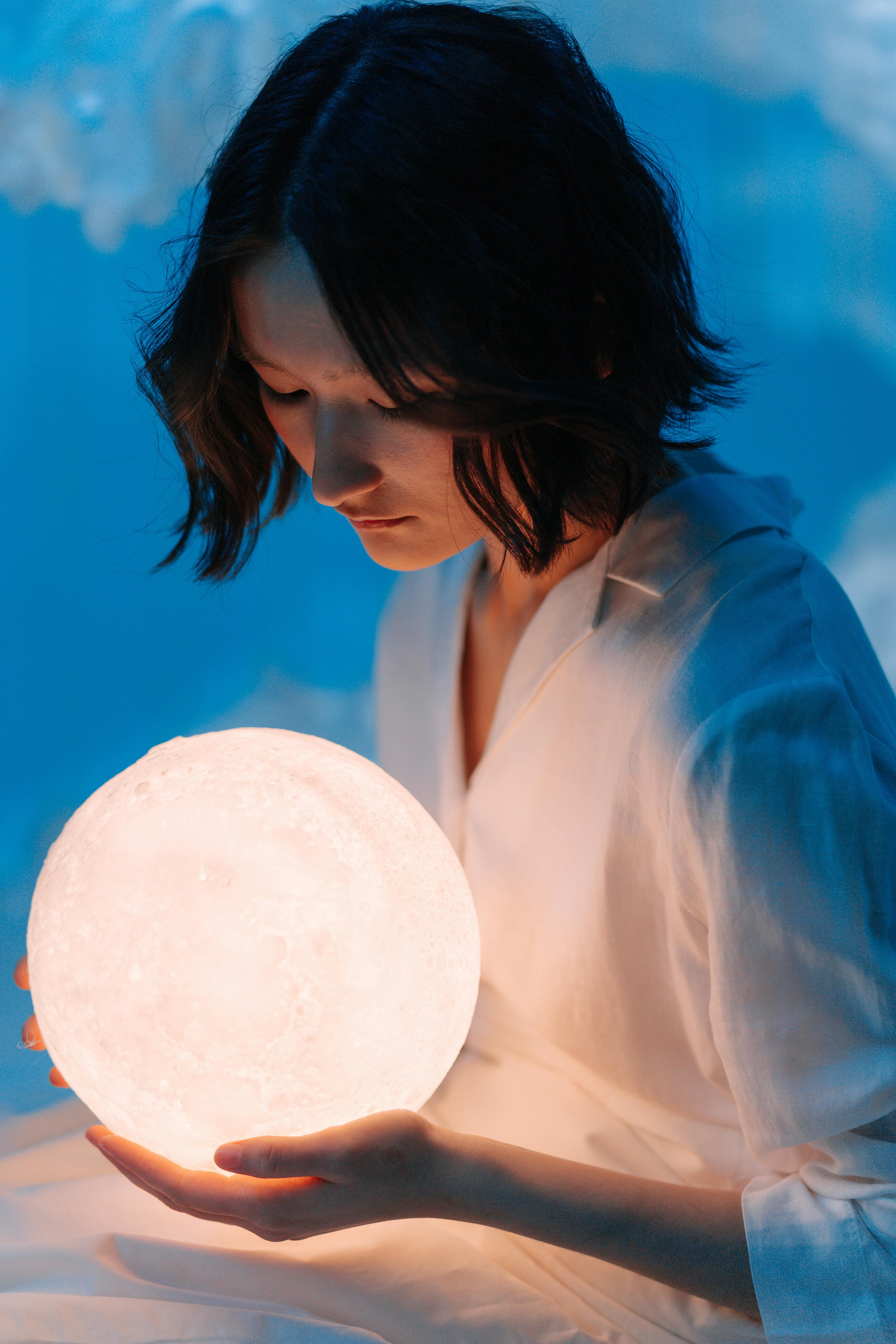 a woman in white top holding a crystal ball