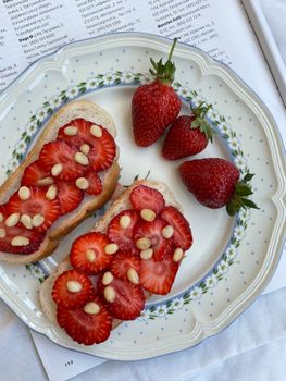 Close-up of sliced strawberries and pine nuts on bread for a delicious snack.