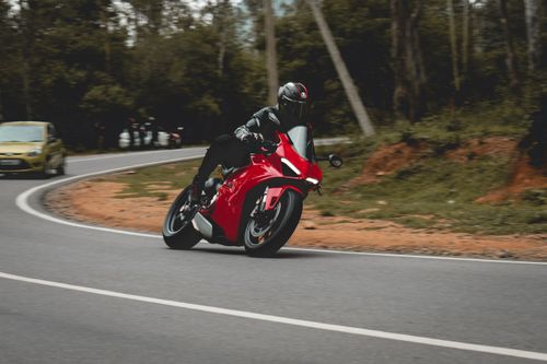 Free A motorcyclist in full gear leans into a turn on a scenic outdoor road. Stock Photo