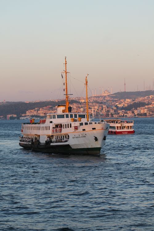 Free A classic ferry boat sailing across the Bosphorus Strait with the Istanbul skyline in the background during sunset. Stock Photo