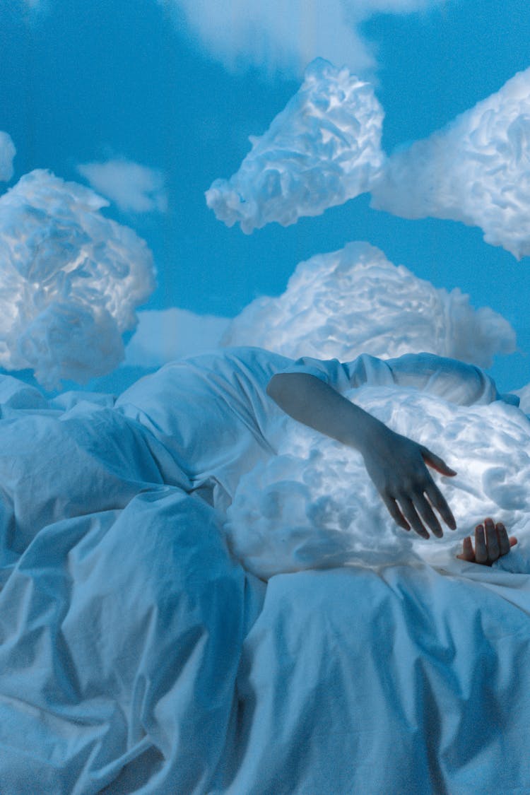 A Person Hugging A Cloud Pillow While Lying On The Bed