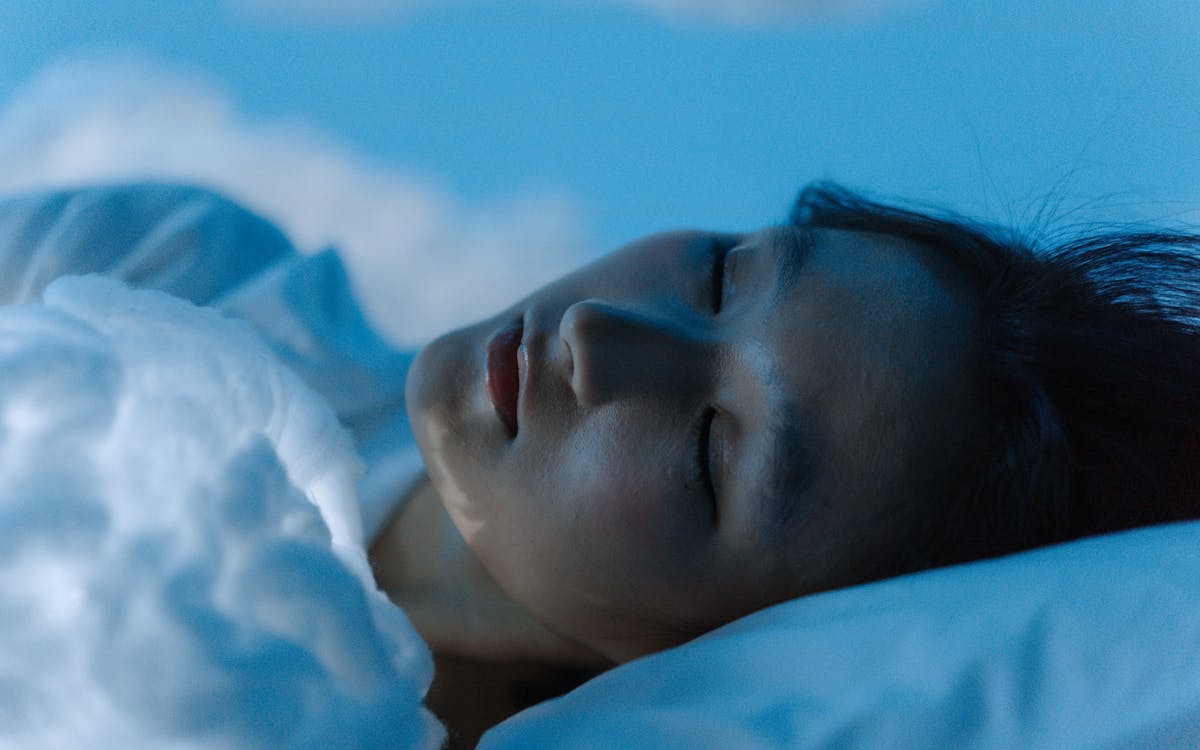 A tranquil scene of a woman sleeping comfortably on a white pillow, evoking peace.