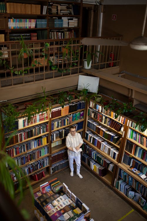 Man Standing Near Bookshelves