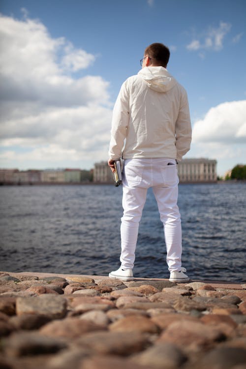 Man in White Clothes Standing Near Body of Water