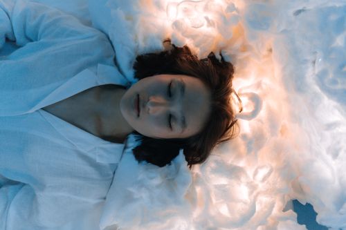 Free Tranquil portrait of a woman lying peacefully on cloud-like surroundings, evoking calmness. Stock Photo