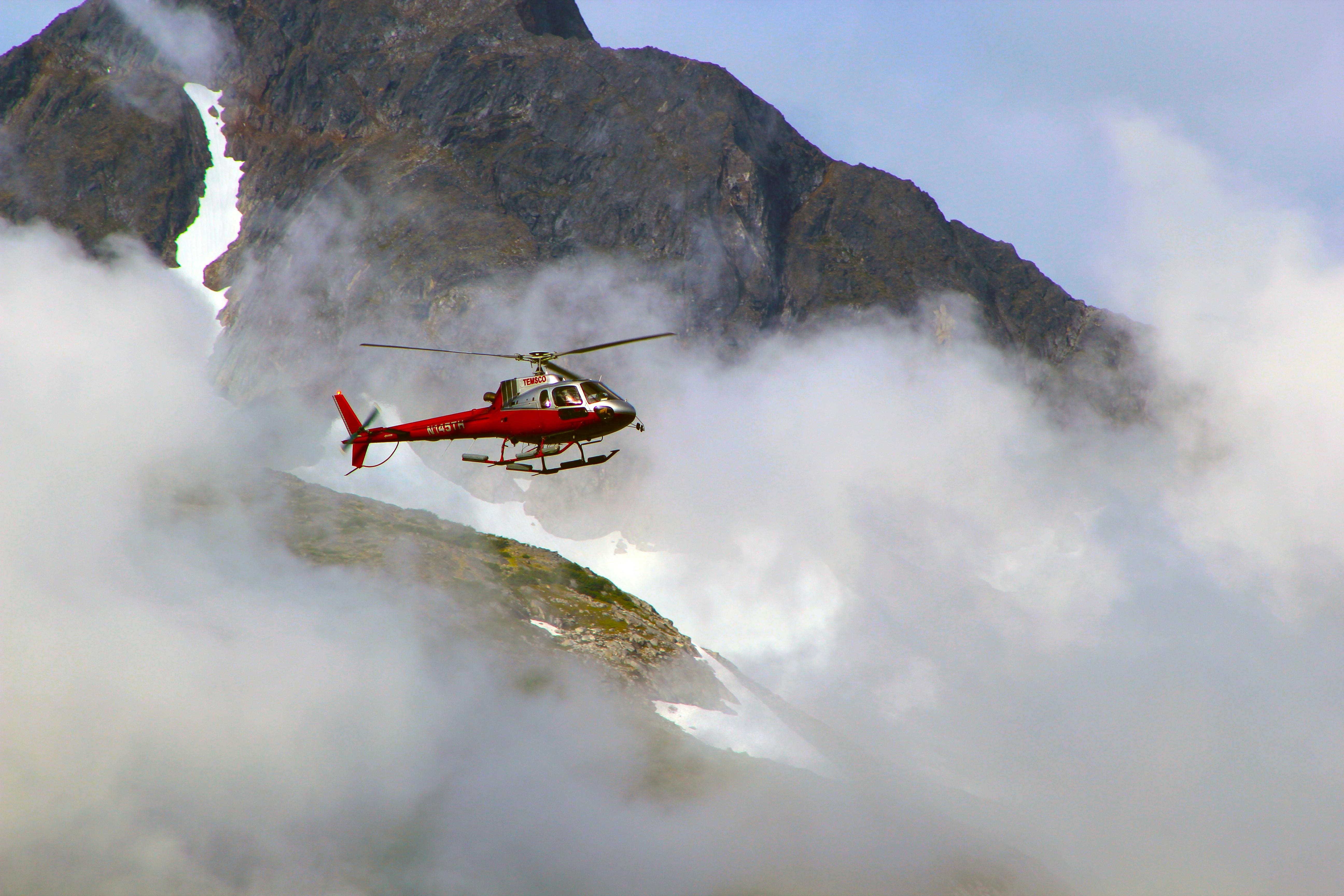 Red helicopter on top of foggy mountain. | Photo: Pexels