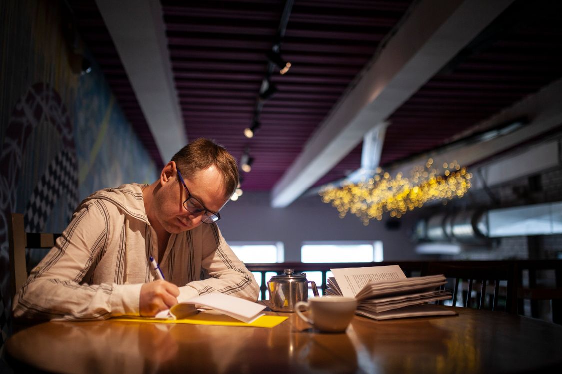 Man Sitting and Writing · Free Stock Photo