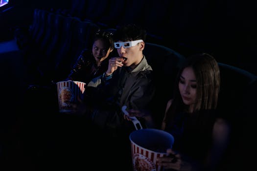 A group of young adults enjoying a movie at the cinema, complete with popcorn and 3D glasses.