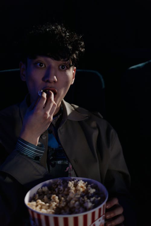 Photo of a Man Eating Popcorn while Watching a Movie