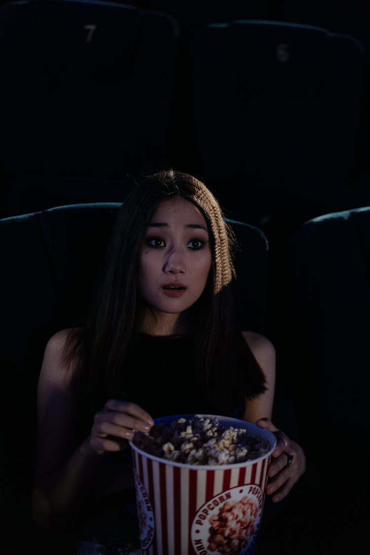 A Beautiful Woman Watching Movie While Holding A Bucket Of Popcorn