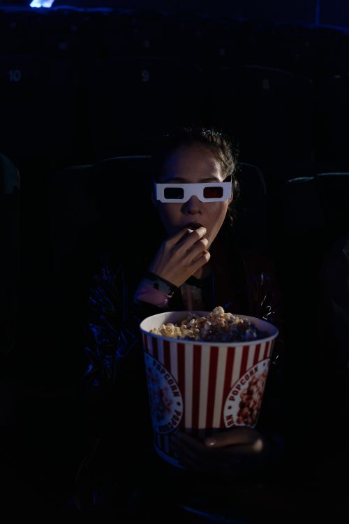 Free Woman eating popcorn while watching a 3D movie in a dark cinema. Stock Photo