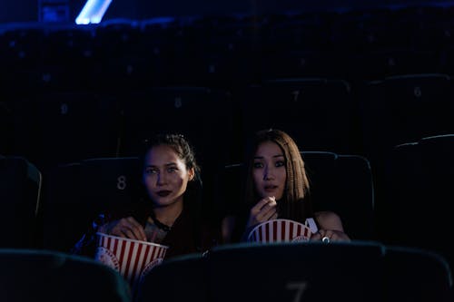 Women Sitting and Eating Popcorn at Cinema