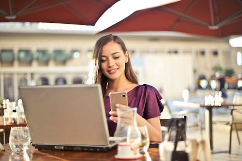 Free Woman Wearing Purple Shirt Holding Smartphone White Sitting on Chair Stock Photo