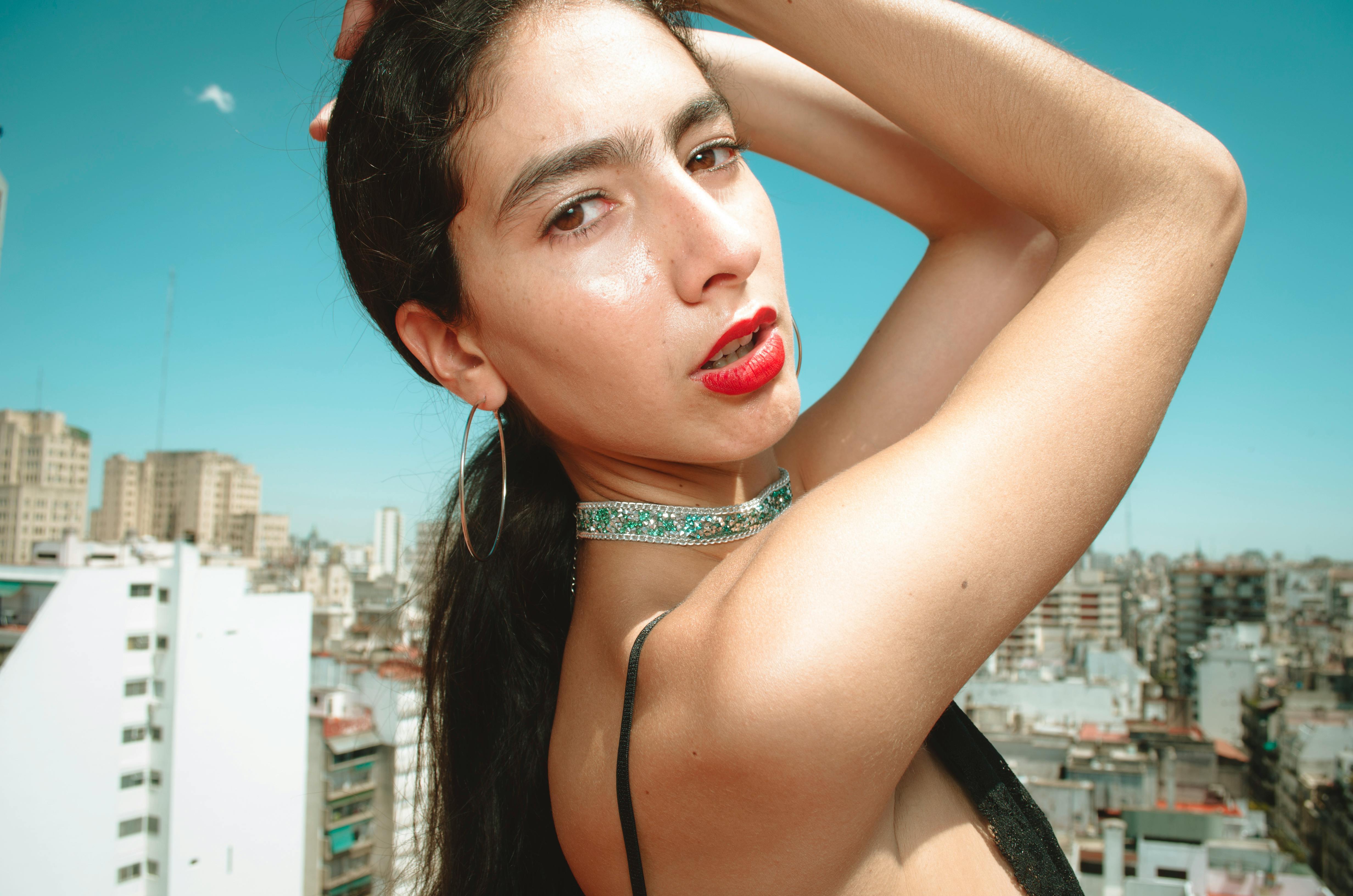 一位年轻的时装模特在城市屋顶上自信地摆姿势，背景是醒目的城市天际线