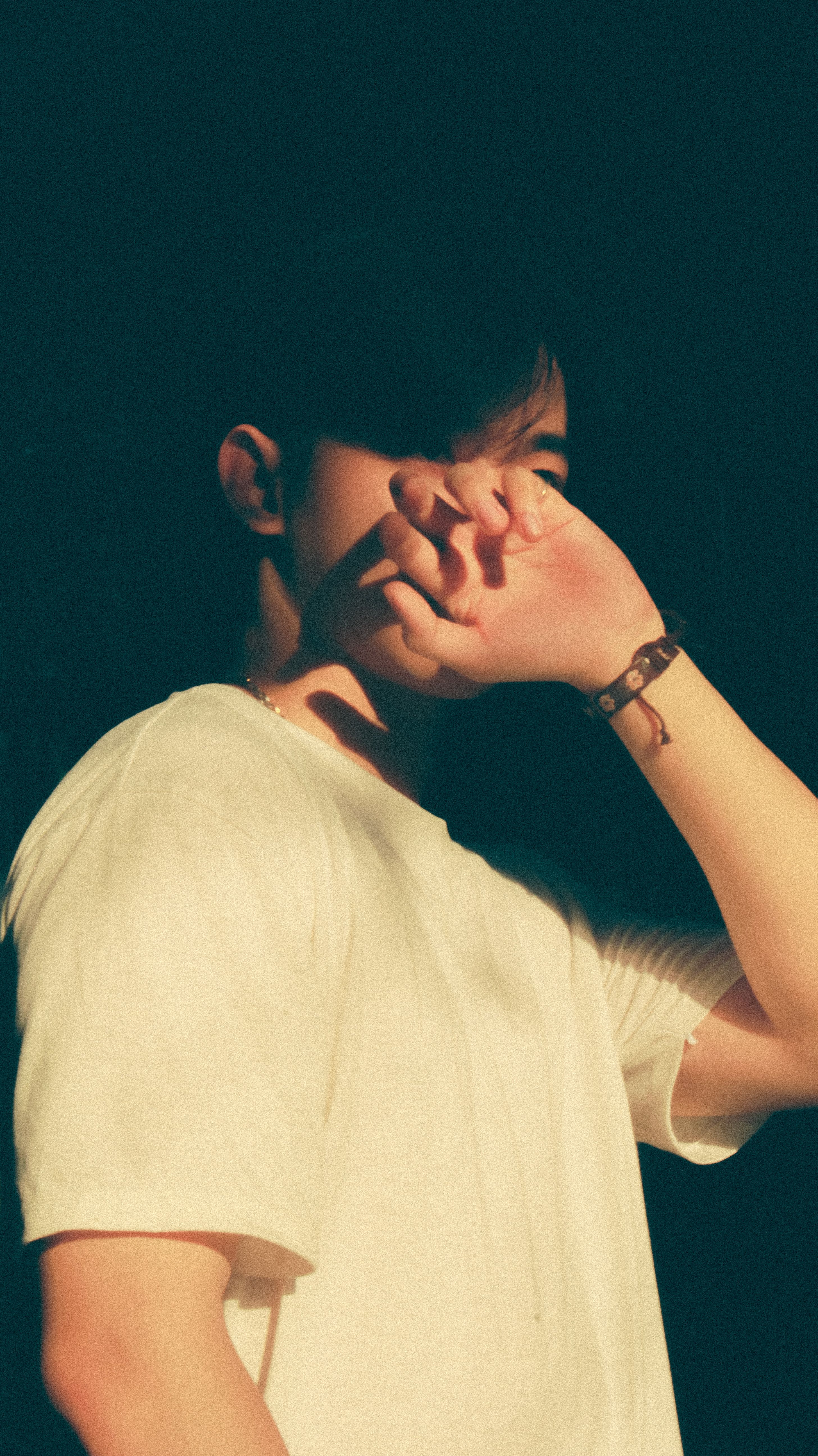 Artistic portrait of a man posing with hand covering face in natural sunlight.