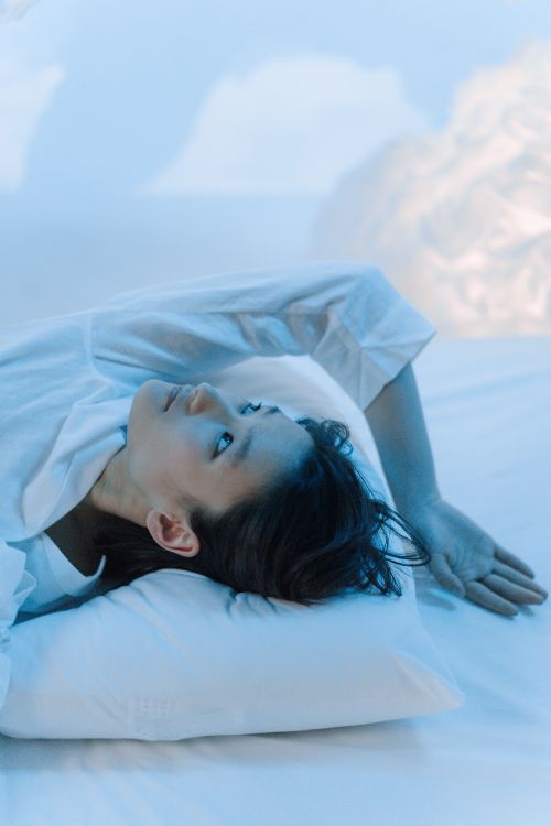 Free A woman in white long sleeves lying down in a tranquil, minimalist setting. Stock Photo