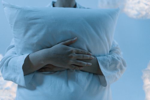 Free A serene scene depicting a person gently hugging a pillow, showcasing calmness and comfort. Stock Photo