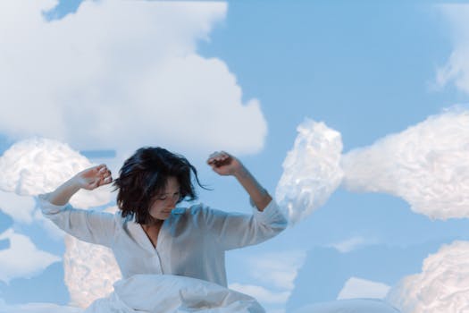 Asian woman with short hair in white shirt surrounded by clouds, evoking peaceful dreaming.