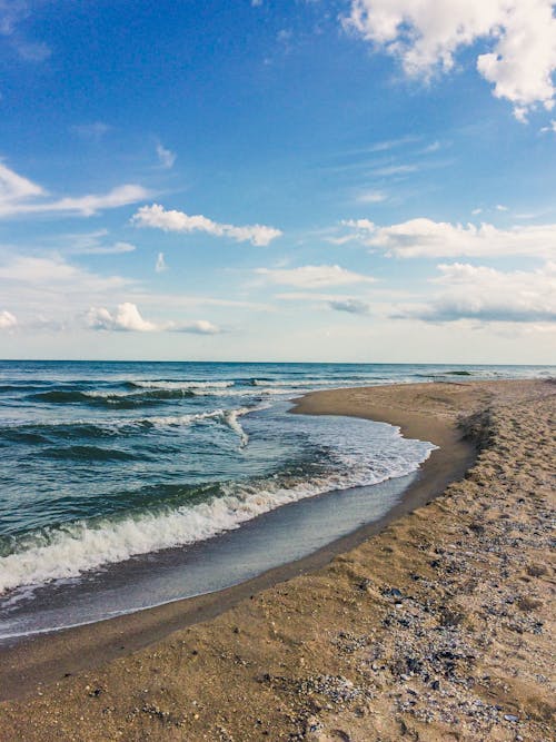 Clear water of sea rolling on sandy coast against blue sky with clouds on summer day in tropical resort in nature