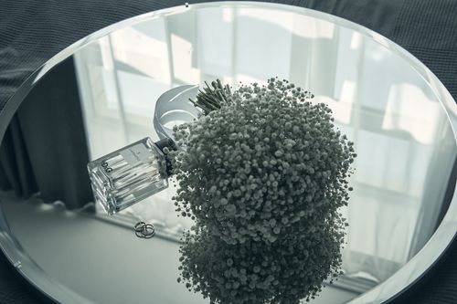 Free A creative still life with perfume bottle, bouquet, wedding rings, and mirror reflections. Stock Photo