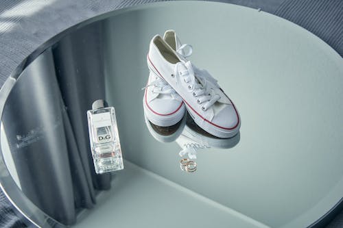 A White Sneakers and Perfume Bottle on the Mirror