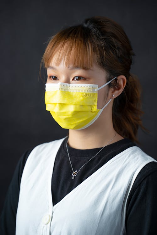 Close-Up Photo of a Woman Wearing a Yellow Face Mask