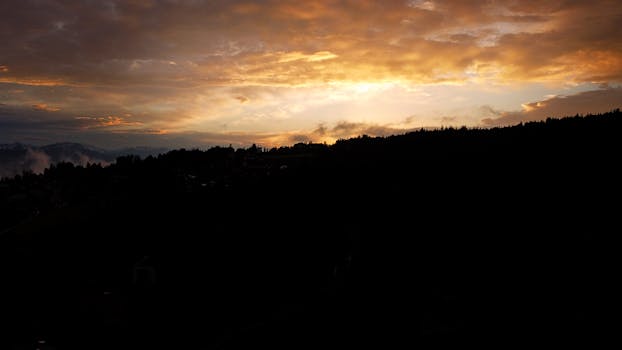 Mesmerizing sunset with dramatic clouds over the silhouette of Trentino mountains.