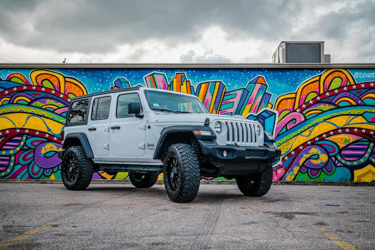 A Low Angle Shot Of A Jeep Parked Near The Wall With Graffiti Art