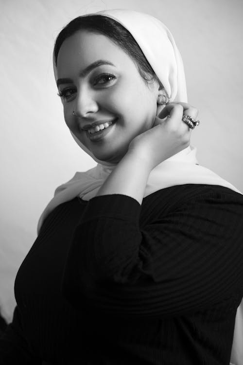 Free Grayscale Photo of a Woman in a Hijab Touching Her Earrings Stock Photo