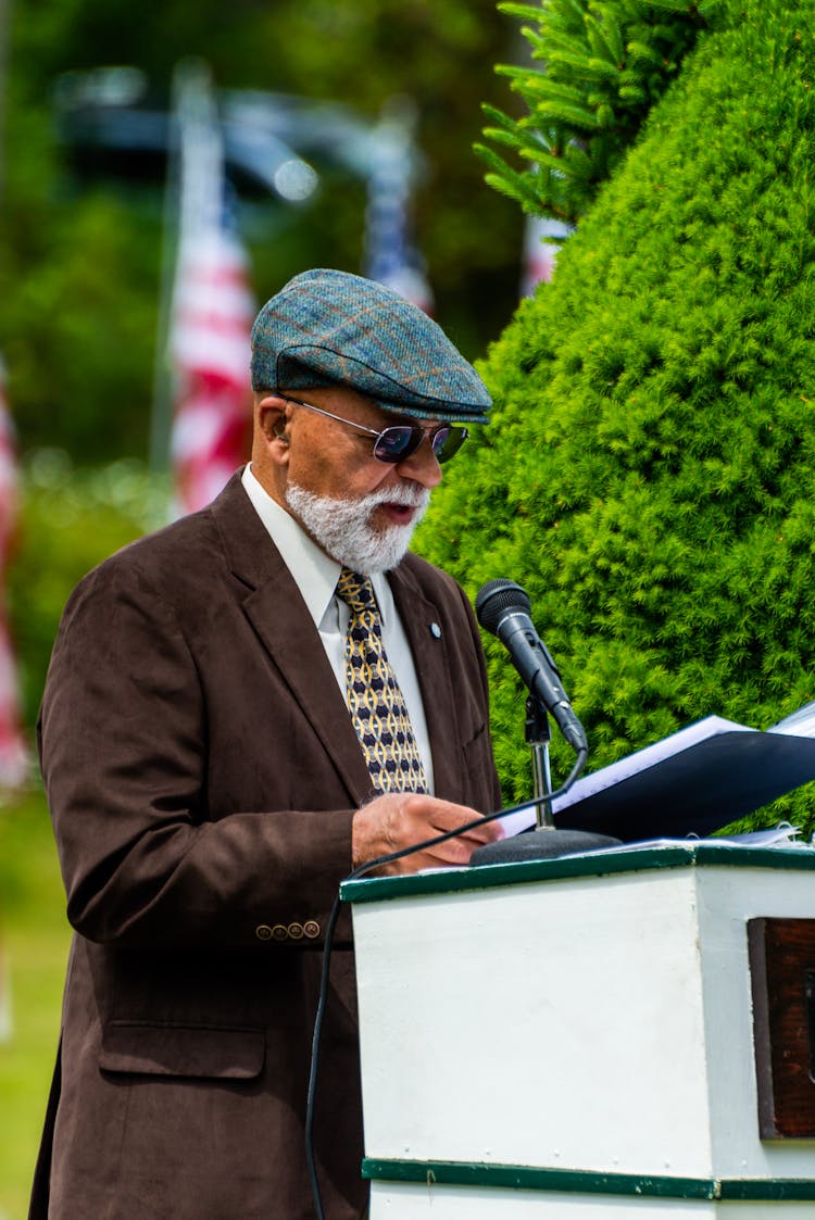 An Elderly Man In Brown Suit Having A Speech