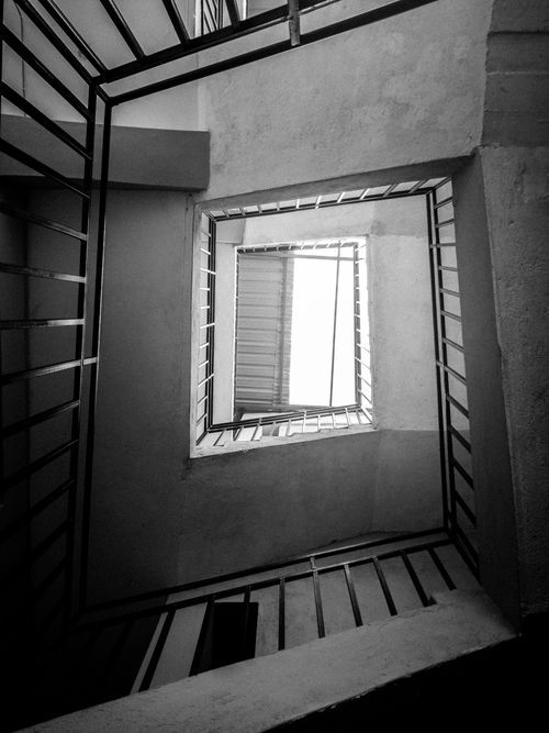 Free Monochrome image of a spiral staircase seen from below, creating a geometric pattern. Stock Photo