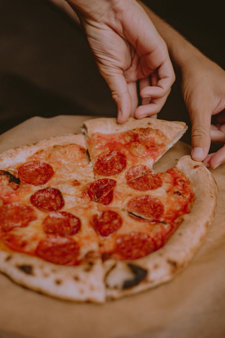 Close-Up Shot Of A Person Getting A Slice Of Pepperoni Pizza